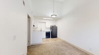 Located at 2120 N Silverbell Rd in Tucson, AZ, this one-bedroom, one-bathroom unit offers a well-organized, single-floor layout designed to maximize functionality. The open living and kitchen area transitions seamlessly between light wood-look flooring and soft carpeting, creating a warm and practical flow throughout the space. The kitchen is thoughtfully equipped with crisp white shaker cabinets, a full suite of black appliances including a refrigerator, dishwasher, and electric range, along with a stainless steel sink and ample counter space. A skylight-style ceiling fixture brightens the kitchen area, complementing the clean, bright aesthetic of the white walls. The bedroom features wall-to-wall carpeting, a textured ceiling, and a window fitted with horizontal blinds that allow for natural light and privacy control. A dedicated closet provides organized storage. The bathroom is finished with wood-look flooring, a white vanity with a granite-style countertop, brushed nickel fixtures, and a full tub-shower combination with tiled surround. The overall design is clean, neutral, and move-in ready, making this a practical and comfortable home in Tucson.