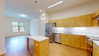 Located at 699 County Road 631 in Charlottesville, VA, this single-floor 2-bedroom, 2-bathroom home offers a clean, modern design with a consistent warm aesthetic throughout. The open-concept kitchen, dining, and living area serves as the heart of the home, showcasing light maple cabinetry extending to the ceiling, stainless steel appliances including a French door refrigerator, dishwasher, and electric range with hood, and a central island with a white countertop and pendant lighting above. Light hardwood flooring runs throughout the entire unit, enhancing the bright, airy feel. Both bedrooms are well-proportioned, featuring neutral white walls, large windows that invite natural light and outdoor views of the surrounding greenery, and dedicated closet space. Three closets in total provide ample storage. The two bathrooms are finished with matching maple vanities, mirrors with overhead lighting, and hardwood-style flooring; one bathroom includes a full soaking tub with built-in shelving. Additional functional spaces include a dedicated laundry room and a utility room. The home's consistent use of light tones, natural materials, and abundant natural light creates a cohesive, comfortable living environment.