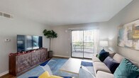 Located at 5500 De Soto St in Houston, TX, this one-bedroom, one-bathroom unit offers a thoughtfully designed layout that maximizes every square foot of living space. The open-concept living and kitchen area forms the heart of the home, with light wood-tone flooring flowing throughout. The living area is bright and welcoming, anchored by a large sliding glass door that opens onto a private balcony, allowing natural light to pour in while offering views of lush outdoor greenery. The galley-style kitchen is well-appointed with dark espresso cabinetry, light countertops, stainless steel appliances including a refrigerator and range, and a double-basin sink — providing ample functionality in an efficient footprint. A hallway connects the main living area to the private bedroom, which features plush carpeting, a ceiling fan, a natural light window, and access to a walk-in closet. The bathroom is clean and modern, featuring dark wood vanity cabinetry, a large mirror with bright vanity lighting, and light wood-tone tile flooring. Additional highlights include a dedicated laundry area and two closets for generous storage. Neutral gray tones throughout create a calm, cohesive ambiance across this well-organized Houston residence.
