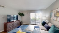 Located at 5500 De Soto St in Houston, TX, this one-bedroom, one-bathroom unit offers a thoughtfully designed layout that maximizes every square foot of living space. The open-concept living and kitchen area forms the heart of the home, with light wood-tone flooring flowing throughout. The living area is bright and welcoming, anchored by a large sliding glass door that opens onto a private balcony, allowing natural light to pour in while offering views of lush outdoor greenery. The galley-style kitchen is well-appointed with dark espresso cabinetry, light countertops, stainless steel appliances including a refrigerator and range, and a double-basin sink — providing ample functionality in an efficient footprint. A hallway connects the main living area to the private bedroom, which features plush carpeting, a ceiling fan, a natural light window, and access to a walk-in closet. The bathroom is clean and modern, featuring dark wood vanity cabinetry, a large mirror with bright vanity lighting, and light wood-tone tile flooring. Additional highlights include a dedicated laundry area and two closets for generous storage. Neutral gray tones throughout create a calm, cohesive ambiance across this well-organized Houston residence.