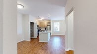 Located at 204 Potters Bluff Dr in Panama City Beach, FL, this well-appointed single-floor residence offers a smart, functional layout making efficient use of its space. The open-concept kitchen serves as the heart of the home, featuring light wood cabinetry, stainless steel appliances, a central island with a white countertop and undermount sink, and stylish globe pendant lighting. An adjacent open pantry provides generous built-in shelving for additional storage. Warm hardwood-style flooring flows throughout the main living areas, enhancing the bright, cohesive feel of the space. The living room is filled with natural light from a sliding glass door that opens to an outdoor view with lush greenery. The bedroom offers plush carpeting, a ceiling fan, and a natural light source through a window, creating a comfortable, restful retreat. A dedicated walk-in closet with wire shelving and hanging rods provides practical storage. The full bathroom features a tile-surround soaking tub and shower combination, a single-sink vanity with granite-style countertop, and a large mirror. A dedicated laundry area with washer hookups and a wire storage shelf rounds out this thoughtfully equipped home.