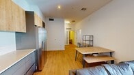 This contemporary 1220 square foot apartment, located in the heart of downtown, offers a harmonious blend of style and functionality. The open-plan living area seamlessly integrates the kitchen, dining, and living spaces, creating a fluid and spacious atmosphere. The kitchen boasts sleek, two-tone cabinetry with light wood upper cabinets and grey lower units, complemented by stainless steel appliances and a clean white backsplash.

Natural light floods the space through large sliding glass doors, leading to a private balcony with glass railings, offering urban views and outdoor seating. The living area features modern furnishings, including a comfortable grey sofa and a vibrant orange accent chair, anchored by light wood flooring throughout.

Two bedrooms provide ample space, with the primary bedroom measuring 240 square feet. Both bedrooms showcase minimalist design with built-in wooden wardrobes and comfortable beds. The two bathrooms are finished with neutral-toned tiles, modern fixtures, and glass-enclosed showers, embodying a spa-like ambiance.

Throughout the apartment, a cohesive color palette of whites, greys, and warm woods creates a calming and contemporary aesthetic. Thoughtful details such as recessed lighting, artistic wall decor, and strategic furniture placement maximize the sense of space and functionality in this urban oasis.