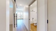 Located at 6901 Flying Cloud Dr in Eden Prairie, MN, this thoughtfully designed one-bedroom, one-bathroom unit maximizes every inch of its compact footprint. The open layout is anchored by light-toned hardwood-style flooring that flows throughout the main living areas, creating a clean and cohesive aesthetic.

The kitchen is a standout feature, outfitted with crisp white shaker cabinetry, light stone countertops, a classic white subway tile backsplash, and a full suite of stainless steel appliances including a range, built-in microwave, dishwasher, and refrigerator. A single-basin sink with a matte black faucet adds a modern touch.

A hallway with sleek black-hardware barn-style sliding doors leads to the bathroom and bedroom. The bathroom is finished in a clean, all-white palette with wood-look flooring, a soaking tub and shower combo, matte black fixtures, and a vanity with a stone-look countertop. The bedroom is a cozy, carpeted retreat with neutral walls and ample natural light. An adjacent walk-in closet features multi-tiered wire shelving and carpeted flooring, offering organized storage. Large windows throughout the unit bring in generous natural light and views of the surrounding Eden Prairie community.