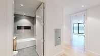 Located at 44 Hudson St in Yonkers, NY, this modern 2-bedroom, 2-bathroom residence offers a thoughtfully designed open-concept layout with high-end finishes throughout. The living, dining, and kitchen areas flow seamlessly together, anchored by a dramatic curved wall of floor-to-ceiling black-framed windows that frame panoramic views of the Yonkers skyline and the Hudson River beyond, flooding the space with natural light. Light-toned hardwood floors run throughout, complementing the clean, contemporary aesthetic.

The kitchen is outfitted with two-tone cabinetry in natural wood and soft grey, a striking marble-look tile floor, stainless steel appliances including a range, dishwasher, microwave, and refrigerator, and ample upper and lower storage.

Both bedrooms are well-proportioned, featuring hardwood floors, recessed lighting, and large windows. The spacious primary bedroom includes a wall-mounted split HVAC unit and direct access to the outdoors. Four closets provide generous storage across the unit.

The two bathrooms are finished with large-format grey stone tiles, soaking tubs, glass-enclosed showers with built-in niches, and warm wood vanities with integrated sinks. Additional conveniences include an in-unit laundry area and a dedicated entrance hallway, completing this polished and functional urban residence.