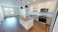 This contemporary 960 square foot apartment in Kingston, MA, offers a thoughtfully designed living space with two bedrooms and two bathrooms. The open-concept layout maximizes the use of space, creating a seamless flow between the living areas. The kitchen is a highlight, featuring sleek cabinetry, granite countertops, and stainless steel appliances, including a dishwasher and a convenient stacked washer-dryer unit.

Both bedrooms are generously sized, with the primary bedroom measuring 150 square feet. Large windows in each room flood the space with natural light, while ceiling fans provide additional comfort. The bathrooms boast modern fixtures, including a tub-shower combination with subway tile surround, and spacious vanities with ample storage.

Throughout the apartment, warm wood-look flooring adds a touch of elegance and warmth. The neutral color palette creates a blank canvas for personal style. Built-in shelving and closets offer practical storage solutions. The attention to detail in the finishes, from the recessed lighting to the stylish pendant lights in the kitchen, elevates the overall aesthetic of this contemporary living space.