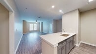 This contemporary apartment at The Quarters At Towson Town Center offers 1,160 square feet of thoughtfully designed living space. The layout includes two bedrooms, two full bathrooms, and an open-concept kitchen and living area. The primary bedroom is generously sized at 230 square feet, providing ample space for relaxation and storage.

The interior showcases a modern aesthetic with neutral tones and high-quality finishes. The kitchen features sleek gray cabinetry, quartz countertops, and stainless steel appliances, including a built-in microwave. A central island with a sink serves as both a functional workspace and a casual dining area.

Both bathrooms boast elegant designs with large vanities, framed mirrors, and glass-enclosed showers. The main bathroom includes a bathtub with white subway tile surround. Throughout the apartment, wood-look vinyl flooring adds warmth and durability.

Large windows in the bedrooms and living areas flood the space with natural light, while ceiling fans provide additional comfort. The apartment's layout includes a hallway connecting the various rooms and two closets for extra storage.

This well-appointed apartment combines style and functionality, offering a comfortable and contemporary living environment in a prime location.