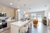 Located at 2320 Clubhouse Station Pl in Waldorf, MD, this well-appointed 2-bedroom, 2-bathroom residence offers a thoughtfully designed single-level layout. The heart of the home is a open-concept living, dining, and kitchen area filled with natural light from large windows. The modern kitchen features light wood cabinetry, sleek white quartz countertops, stainless steel appliances, and a center island with bar seating, accented by globe pendant lighting. The living area flows seamlessly toward a private balcony through a glass-paneled door, providing outdoor views of the surrounding community. Wood-style flooring runs throughout, adding warmth and continuity across the space. The primary bedroom is generously proportioned, with a large window framing outdoor views, and is complemented by a spacious en-suite bathroom featuring a dual-sink vanity with wood-toned cabinetry and a separate shower. The walk-in closet offers extensive wire shelving for organized storage. The second bedroom is equally bright and comfortable. Additional highlights include three closets, an in-unit laundry room, and a second full bathroom. The overall aesthetic is clean and contemporary, with a neutral palette that creates a calm, inviting ambiance throughout.