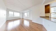 Located at 7 DeKalb in the heart of Brooklyn, NY 11201, this one-bedroom residence offers a clean, contemporary design throughout its single-floor layout. Warm hardwood flooring runs continuously across the space, complementing the crisp white walls and creating a bright, inviting atmosphere.

The living area is generously proportioned, featuring multiple windows that frame elevated views of the surrounding Brooklyn and Manhattan skyline. Natural light fills the room from multiple angles, enhancing the open, airy feel of the space. The layout flows naturally toward a well-appointed kitchen, which features a large peninsula with a quartz countertop and integrated sink, rich dark wood cabinetry, light blue glass tile backsplash, and a full suite of stainless steel appliances including a refrigerator, range, microwave, and dishwasher. A window within the kitchen provides additional natural light and city views.

The bedroom is a comfortable, well-lit room with its own window overlooking the cityscape and includes a double-door closet offering ample storage. Throughout the residence, the design emphasizes clean lines, neutral tones, and functional simplicity, making it a polished urban living space in one of Brooklyn's most vibrant neighborhoods.