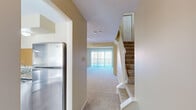 This three-floor property is thoughtfully laid out across distinct levels, each serving a dedicated purpose. The ground floor houses a private garage equipped with an automatic opener, concrete flooring, and block wall construction, providing secure parking and additional storage space.

The main living level features an open layout connecting the kitchen, dining area, and living room. The kitchen is outfitted with rich dark cabinetry, granite countertops, stainless steel appliances including a refrigerator and dishwasher, and wood-look flooring. A pass-through window connects the kitchen to the adjacent dining area, which benefits from a bay window that draws in generous natural light. The living room is carpeted, centered with a ceiling fan, and features a sliding glass door leading to an outdoor balcony. A half bathroom on this level includes granite-topped cabinetry and wood-look flooring.

The upper floor hosts carpeted bedrooms, each featuring multiple windows that invite natural light. One bedroom displays a vaulted ceiling detail, adding architectural interest. Neutral warm tones and textured ceilings are consistent throughout, contributing to a cohesive and comfortable ambiance across all levels.