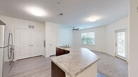 This well-appointed one-bedroom, one-bathroom residence in Hanahan, South Carolina offers a thoughtfully designed single-floor layout. The open-concept kitchen and living area serves as the heart of the home, featuring dark espresso cabinetry, granite countertops, a central island with a sink, and a full suite of stainless steel appliances including a refrigerator, range, microwave, and dishwasher. Light wood-style flooring runs throughout the kitchen, complementing the neutral palette. The living area is brightened by a window overlooking lush greenery and is outfitted with a ceiling fan, while a glass-paneled door provides access to an outdoor area. The spacious primary bedroom features plush carpeting, a ceiling fan, and a large window that invites natural light. A dedicated closet offers organized storage. The bathroom is clean and functional, showcasing a granite-topped vanity with dark cabinetry, a tub-shower combination, and light wood-look tile flooring. Throughout the residence, a consistent light, neutral color scheme and modern finishes create a cohesive and inviting atmosphere.