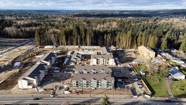 Vista aérea panorámica de la construcción en The Elowen, Lacey, Washington. Nuevos apartamentos toman forma entre los imponentes árboles de hoja perenne en un día soleado del noroeste del Pacífico. - The Elowen