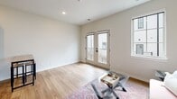 This single-floor residence features a thoughtfully designed layout that prioritizes functionality and modern aesthetics. The kitchen serves as a central highlight, outfitted with rich dark-toned cabinetry, speckled granite countertops, a stainless steel sink, and a full suite of stainless steel appliances including an electric range, built-in microwave, dishwasher, and refrigerator. A white subway tile backsplash adds a clean, contemporary contrast to the warm cabinetry tones. Light hardwood-style flooring runs consistently throughout the unit, creating a cohesive and open feel.

The living area is bright and welcoming, benefiting from natural light provided by a side window and a set of French doors that open to a private balcony, offering outdoor access and additional light. The neutral white walls and recessed lighting further enhance the airy ambiance of the space.

The bathroom continues the design language of the unit, featuring matching dark cabinetry, granite countertops, a tall storage cabinet, and hardwood-style flooring. The space is efficiently organized, with a closet accessible adjacent to the bathroom entry. Overall, the unit presents a clean, modern interior with consistent finishes that create a polished and cohesive living environment.