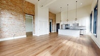 This well-appointed 980 square foot apartment in Hamilton, Ohio, showcases a perfect balance of modern functionality and historic character. The single-floor layout comprises one bedroom, one bathroom, and an open-concept kitchen and living area. Large windows with striking black frames flood the space with natural light, offering picturesque views of the surrounding area. The interior boasts high ceilings and gleaming hardwood floors throughout, creating an airy and spacious ambiance.

The kitchen is a chef's delight, featuring sleek white cabinetry, stainless steel appliances, and elegant granite countertops. Pendant lighting adds a touch of sophistication to the space. The bedroom, measuring 250 square feet, provides ample room and includes a generously sized closet with built-in organizers.

A standout feature is the exposed brick wall in one section of the apartment, adding warmth and texture to the otherwise crisp, white walls. The bathroom continues the modern aesthetic with clean lines and contemporary fixtures. Throughout the apartment, the contrast between the white walls and dark window frames creates a striking visual impact, enhancing the overall design. This thoughtfully renovated space seamlessly blends contemporary comfort with classic architectural elements, resulting in a stylish and inviting home.