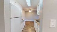 Located at 16077 Ashland Ave in San Lorenzo, CA, this single-floor, 2-bedroom, 1-bathroom residence offers a functional and well-appointed layout. The living room is a standout space, featuring warm hardwood-style flooring, a ceiling fan, and a sliding glass door that opens to a private balcony, flooding the room with natural light and providing outdoor views. The galley-style kitchen is efficiently designed with white cabinetry, stone-toned countertops, white appliances including a refrigerator, range, and dishwasher, and a skylight overhead that brightens the workspace. Hardwood-style flooring continues throughout the kitchen and hallway, creating a cohesive flow. Both bedrooms are carpeted for comfort, offering a quiet retreat. The primary bedroom is a generous size and features a window with neighborhood views, while the second bedroom includes a wall vent and access to the hallway. A dedicated walk-in closet with built-in shelving provides ample storage. The bathroom is clean and modern, featuring a white vanity with a medicine cabinet, a combination shower/tub with sliding glass doors, and hardwood-style flooring. The overall ambiance is clean, neutral, and move-in ready.