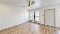 Located at 2800 Douglas Ave in Dallas's Oak Lawn neighborhood, this one-bedroom, two-bathroom unit offers a well-designed single-level layout with clean, modern finishes throughout. Light-toned wood-look flooring runs seamlessly across the living room and bedroom, complementing the crisp white walls and creating a bright, cohesive aesthetic. The living room features a stylish gold-toned ceiling fan, recessed lighting, and a window with blinds that brings in natural light. The spacious primary bedroom is generously sized, boasting its own ceiling fan, mirrored sliding closet doors, and direct access to a private balcony that overlooks green outdoor surroundings. An en-suite bathroom is conveniently accessible from the bedroom. The bathrooms are thoughtfully finished, with one featuring a full soaking tub framed by floor-to-ceiling marble-look tile work, adding an elevated touch. The kitchen includes dark granite countertops and white cabinetry, while a dedicated in-unit laundry closet adds everyday practicality. The overall ambiance is modern and move-in ready, blending functional design with clean architectural details throughout.