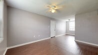 This two-bedroom, two-bathroom apartment at Magnolia Park in Jackson, Mississippi offers a practical and comfortable single-floor layout. Consistent warm-toned wood-style flooring runs throughout the unit, providing a cohesive look across all living spaces. The living area is open and well-proportioned, featuring a ceiling fan with light fixture, neutral gray walls, and a textured ceiling. Natural light enters through windows fitted with blinds, creating a bright and airy atmosphere. An adjacent kitchen is equipped with warm oak-toned cabinetry, a white electric range with overhead ventilation, a double sink, and a tiled backsplash, offering ample storage and counter space for everyday cooking needs. Both bedrooms are comfortably sized, each featuring a ceiling fan, wood-style flooring, and windows that allow in natural light with views of the surrounding community. A hallway connects the bedrooms to the two bathrooms, one of which includes a full tub-shower combination, pedestal sink, toilet, and vanity mirror with overhead lighting. Closet storage is also accessible from the hallway, adding to the unit's overall functionality.