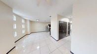 This single-story, 2-bedroom, 2-bathroom home offers a practical and cohesive layout designed for comfortable everyday living. The open living area greets you upon entry, featuring gleaming large-format white tile flooring that extends throughout the entire home, creating a seamless and easy-to-maintain surface. Stacked windows along the living room walls allow generous natural light to fill the space, while a ceiling fan enhances airflow and comfort. Dark-stained six-panel interior doors provide a consistent design contrast against the warm neutral-toned walls.

The kitchen is well-equipped, showcasing dark cabinetry paired with granite-look countertops, stainless steel appliances including a French-door refrigerator and electric range, a wall-mounted range hood, and a stainless steel sink — offering both style and functionality.

The primary bedroom is a comfortable, well-proportioned retreat with its own ceiling fan and a window for natural light. The second bedroom is similarly appointed, also featuring a ceiling fan, a window, and access to the electrical panel.

The two bathrooms are finished in tile, with one featuring a tiled walk-in shower with a mosaic accent border. A dedicated utility room completes the layout, rounding out this efficiently designed home.