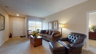 Located at 5423 Waterford Cir in Sheffield, Ohio, this single-floor residence offers a thoughtfully designed layout with a warm, cohesive aesthetic throughout. The living room serves as a welcoming centerpiece, featuring plush carpeting, neutral walls, and multiple windows that allow natural light to fill the space. The room comfortably accommodates generous seating arrangements, creating an inviting atmosphere for relaxation.

Adjacent to the living area is a dedicated dining nook, providing an intimate setting for meals. The kitchen is well-equipped with rich cherry wood cabinetry, granite countertops, tile flooring, and recessed lighting. A central island with bar seating adds both functionality and additional prep space, while white appliances, including a dishwasher and refrigerator, complete the layout. A hallway from the kitchen provides convenient access to additional rooms.

The primary bedroom is generously sized with soft carpeting and direct access to a walk-in closet and an en-suite bathroom featuring a vanity with cherry cabinetry and a glass-enclosed shower. A secondary bedroom offers a bright, versatile space with a large window and ample room. The second full bathroom includes a tub-shower combination and matching cherry vanity cabinetry, maintaining a consistent design language found throughout the home.