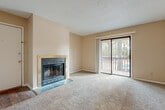 This single-story, one-bedroom, one-bathroom unit offers a well-organized layout across a comfortable footprint. The living room serves as the focal point of the home, anchored by a wood-burning fireplace with a tile hearth and framed by neutral carpet throughout. A full-width sliding glass door opens to a private balcony overlooking mature trees, filling the space with natural light and outdoor views. Textured ceilings are present throughout the unit.

Adjacent to the living area, the dining space features warm hardwood-style flooring and an elegant chandelier overhead, creating a defined area for meals. This space connects directly to the kitchen, which is equipped with rich wood cabinetry, light countertops, a double-basin sink, and a dishwasher, offering practical storage and functionality.

The bedroom provides a carpeted retreat with a ceiling fan, a window for natural light, and convenient access to the hallway. The full bathroom includes a wood-vanity with light countertop, a large mirror, and a tub/shower combo, finished with hardwood-style flooring for a clean, cohesive look throughout.
