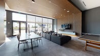 Located at 3163 SW 22nd Terrace in Miami's Coconut Grove neighborhood, this single-floor space showcases a sleek, contemporary design defined by high-end finishes and an open, flowing layout. The interior is anchored by a striking wood-slat ceiling that adds warmth and texture, complementing the large-format grey tile flooring found throughout.

The expansive main living area features a generous sectional sofa arrangement centered around a wall-mounted flat-screen television set against a richly textured vertical wood-panel accent wall with integrated floating media storage. Floor-to-ceiling windows with roller shades flood the space with natural light and provide direct views of an outdoor patio area, which is visible with seating and shade umbrellas beyond.

A dining table with modern chairs occupies one side of the open-plan area, while a ping-pong table adds a recreational element to the layout. The kitchen is outfitted with dark cabinetry, white upper cabinets, a stainless steel refrigerator, and a substantial marble-topped island with bar seating. A secondary seating nook near the entry features high ceilings and access to additional rooms, completing this refined and versatile Miami retreat.