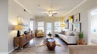 This single-floor residence offers a thoughtfully designed layout that balances comfort and functionality throughout. The living room serves as the heart of the home, showcasing wood-style flooring, crown molding, and a ceiling fan overhead. Multiple windows invite an abundance of natural light, while a set of glass-paned doors opens to an outdoor area, enhancing the sense of openness. The space is well-proportioned, offering ample room for both relaxing and entertaining.

Adjacent to the living area, the dining room provides an intimate setting framed by neutral walls and curated wall art, creating a refined atmosphere for shared meals. The kitchen is outfitted with rich dark cabinetry, stainless steel appliances, and a generous white quartz island that serves as both a prep surface and a casual gathering spot. Wood-style flooring continues here, and an in-unit laundry area is conveniently located nearby.

The bedroom is a serene retreat featuring plush carpeting, a ceiling fan, and a large window that fills the room with natural light. It connects directly to a spacious walk-in closet equipped with built-in wire shelving and carpet flooring, offering excellent storage capacity. The bathroom complements the bedroom suite with dark wood cabinetry and wood-style tile flooring, completing this well-rounded and cohesive living space.