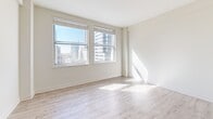 Located in Penn Street Tower in the heart of downtown Indianapolis, this two-bedroom, one-bathroom unit offers a compact yet efficiently designed single-floor layout. The living room is a bright, open space highlighted by large windows that frame impressive views of the Indianapolis skyline, allowing natural light to pour across the light-toned hardwood-style flooring. An open pass-through connects the living area to the kitchen, which features light cabinetry, a tile backsplash, stone-look countertops, and a pendant light fixture, creating a functional and cohesive space. Both bedrooms are carpeted and finished in neutral tones; the primary bedroom benefits from a large window with additional city views, while the second bedroom offers a quiet, understated layout. The full bathroom is finished with tile flooring, a white vanity with a stone-look countertop, a wall-mounted mirror, and classic light fixtures, maintaining the clean aesthetic found throughout the unit. A hallway connects the key areas of the floor plan, contributing to a logical and easy-to-navigate flow. The consistently light color palette and neutral finishes throughout create a bright, clean ambiance well-suited to urban living in downtown Indianapolis.