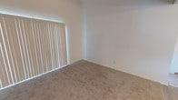 This single-floor residence offers a clean, functional layout with notable architectural details throughout. The bedrooms are generously proportioned, featuring soaring vaulted ceilings that amplify the sense of openness and volume. Plush wall-to-wall carpeting provides warmth underfoot, while large windows dressed with vertical blinds allow abundant natural light to fill the spaces and offer adjustable privacy.

The kitchen is designed in a practical U-shaped configuration, maximizing counter and storage space. White cabinetry lines the walls from floor to ceiling, complemented by white countertops and light wood-look flooring that lends a fresh, airy feel. The kitchen is equipped with a gas range, dishwasher, and a double-basin sink positioned beneath a window, offering natural light while cooking or cleaning. Overhead flush-mount lighting ensures the space remains well-lit throughout the day.

The bathroom features light wood-look flooring consistent with the kitchen, neutral walls, and a mirrored medicine cabinet above the vanity. A towel bar and shower with a decorative curtain complete the space, keeping it tidy and efficient. Throughout the residence, a neutral color palette of whites and warm beiges creates a cohesive, calm ambiance that is both inviting and easy to personalize.