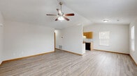 This single-story, one-bedroom, one-bathroom unit offers an efficient and functional layout spread across a single floor. The combined living, dining, and kitchen area forms the heart of the home, featuring durable hardwood-style plank flooring and a ceiling fan with integrated lighting that enhances air circulation and ambiance. Vaulted ceiling lines in the main living space add a sense of openness beyond what the footprint might suggest.

The galley-style kitchen is well-appointed with warm honey-toned oak cabinetry lining both walls, offering ample upper and lower storage. It includes a coil-top electric range, a built-in dishwasher, a refrigerator, a sink, and a ventilation hood. A pantry door at the end of the kitchen provides additional storage convenience. Light-colored countertops complement the cabinetry throughout.

The bedroom is a comfortable, private retreat with its own ceiling fan, a window overlooking the outdoors, and access to a dedicated closet. The clean, neutral walls and consistent hardwood-style flooring carry through from the main living areas.

The bathroom features a full-size soaking tub and shower combination with clean white surrounds and chrome fixtures, maintaining a simple and practical aesthetic. White trim and neutral tones throughout the unit create a cohesive, move-in-ready environment.