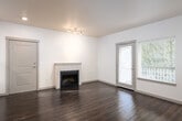 This single-floor residence offers a thoughtfully designed layout with a cohesive blend of modern finishes and functional living spaces. The open living area serves as the heart of the home, showcasing rich dark hardwood flooring that reflects natural light pouring in through a sliding glass door that leads to a private balcony with views of surrounding trees. A classic fireplace with a clean white surround anchors the living space, adding warmth and character. Track lighting accents the room's neutral, light-toned walls.

The kitchen is outfitted with light wood cabinetry, white quartz-style countertops, and stainless steel appliances including an electric range and over-the-range microwave, offering both style and practicality.

The bathrooms feature the same light wood cabinetry with brushed nickel hardware, white countertops, and a full tub-shower combination, maintaining a consistent modern aesthetic throughout.

The bedrooms are carpeted for comfort and filled with natural light through large windows with views of lush greenery. One bedroom includes an en-suite bath, adding convenience and privacy.

Overall, this residence presents a clean, contemporary design with warm touches, practical finishes, and a strong connection to natural surroundings.