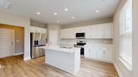 Located at 2762 Lascassas Pike in Murfreesboro, Tennessee, this two-story home features a clean, contemporary design spread across two well-proportioned floors. The main level hosts an open-concept kitchen and living area finished with light hardwood-style flooring and recessed lighting throughout. The kitchen is a standout feature, boasting white shaker cabinetry, white quartz countertops, a central island with an undermount sink, and a full suite of stainless steel appliances. Natural light filters in through windows dressed with white blinds, enhancing the home's bright and airy atmosphere. The attached garage offers generous space with a panel-style door, opener, and a clean concrete floor. Upstairs, carpeted bedrooms provide comfort and quiet, including a spacious primary suite with its own walk-in closet fitted with wire shelving. The primary bathroom features white cabinetry, a dual-sink vanity with quartz counters, and hardwood-style flooring. Additional bedrooms are well-sized with their own closets. A dedicated laundry room with overhead wire shelving adds everyday convenience. Neutral warm-gray tones, panel-style interior doors, and consistent finishes throughout give this home a cohesive, move-in-ready appeal.