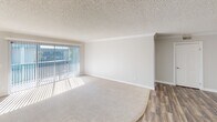 Located on Pickwick Circle in Huntington Beach, California, this single-story residence offers a bright, neutral interior designed for comfortable coastal living. The open living and dining area is finished with plush carpeting and features a textured ceiling with crown molding trim. A large sliding glass door fitted with vertical blinds draws in generous natural light and provides access to an outdoor area, creating a seamless indoor-outdoor connection.

The kitchen is well-appointed with white shaker-style cabinetry extending to the ceiling, dark granite countertops, a double-basin sink, and a full suite of stainless steel appliances including a refrigerator, electric range, microwave, and dishwasher. Wood-look flooring runs throughout the kitchen, adding warmth and contrast to the bright cabinetry.

The bedrooms are carpeted and receive natural light through sliding glass doors with vertical blinds. One bedroom includes a walk-in closet, while additional rooms offer ample wall space accented by crown molding.

The bathrooms are finished with granite-topped vanities, cream cabinetry, large mirrors with overhead lighting, and wood-look tile flooring, contributing to a cohesive and updated aesthetic throughout the home.