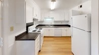 Located at 1153 Salem Dr in Charlotte, NC, this two-floor home offers a clean, functional layout with a neutral color palette throughout. The main level features warm hardwood flooring that flows through the living areas and kitchen. The kitchen is well-equipped with white shaker-style cabinetry, dark granite-style countertops, a double-basin sink, and white appliances including a range, dishwasher, and refrigerator. A sliding door provides direct access to the fenced outdoor area, allowing for natural light and easy outdoor flow. The living and dining areas are bright and open, with windows that invite natural light and views of the surrounding greenery. Upstairs, the bedrooms are finished with plush carpeting and feature windows overlooking the outdoors. The primary bedroom includes an en-suite bathroom access, while additional bedrooms offer walk-in closet space. The full bathroom is finished with white tile surrounding a soaking tub and shower combination, complemented by hardwood flooring and clean white walls. Crown molding and consistent trim work add a refined touch throughout the home, contributing to its tidy and well-maintained character.