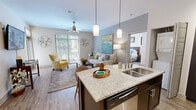 Located at 300 State St in downtown Knoxville, TN, this well-appointed 2-bedroom, 2-bathroom residence offers a thoughtfully designed single-level layout. The open-concept kitchen and living area serves as the heart of the home, featuring a granite-topped island with a stainless steel sink and pendant lighting overhead. Dark espresso cabinetry, a white subway tile backsplash, stainless steel appliances—including a side-by-side refrigerator, electric range, and built-in microwave—and wood-look flooring give the kitchen a polished, modern aesthetic. A stacked washer/dryer unit is conveniently tucked nearby. The living room is bright and welcoming, bathed in natural light through large sliding glass doors and windows fitted with blinds. A ceiling fan adds comfort, and the open sightlines between the kitchen and living area create a spacious, connected feel. The primary bedroom offers plush carpeting, a ceiling fan, a generous closet, and a large window overlooking greenery. The second bedroom mirrors this comfortable design. Both bathrooms are finished with dark vanity cabinetry, granite countertops, framed mirrors, and tile flooring, offering a consistent, refined look throughout the residence.