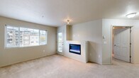 This thoughtfully designed two-bedroom, two-bathroom residence offers a functional and comfortable single-floor layout. The open-concept living room serves as the heart of the home, featuring plush wall-to-wall carpeting, a built-in electric fireplace set into a half-wall partition, and a large window alongside a glass balcony door that floods the space with natural light and provides outdoor views.

The kitchen is well-equipped with warm wood cabinetry, dark granite-style countertops, stainless steel appliances including a refrigerator, range, microwave, and dishwasher, and light hardwood flooring that adds a clean contrast to the cabinetry. A raised breakfast bar separates the kitchen from the adjacent living area.

The two bedrooms are carpeted and neutrally finished, with the primary bedroom offering a generous footprint. Both bathrooms include a full tub-shower combination with white tile surrounds, providing clean and functional spaces. A dedicated closet area houses a stacked washer and dryer unit, offering the convenience of in-unit laundry.

Throughout the residence, neutral tones, textured ceilings, and consistent finishes create a cohesive and move-in-ready atmosphere suitable for a variety of lifestyles.