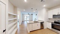 Located at 760 Airport Blvd in Austin, TX, this modern one-bedroom, one-bathroom unit offers a thoughtfully designed open-concept layout finished with contemporary details throughout. Light wood flooring flows seamlessly across the entire space, creating a warm and cohesive aesthetic.

The kitchen serves as the centerpiece of the main living area, anchored by a spacious island with a quartz countertop, an undermount sink, and a sleek matte black faucet. Striking black pendant lights hang above the island, complementing the white shaker cabinetry with black hardware. Stainless steel appliances — including a refrigerator with ice maker, electric range, microwave, and dishwasher — complete the well-equipped kitchen. A built-in shelving unit adjacent to the kitchen provides additional storage and display space. The open living area beyond benefits from natural light streaming through French doors and a ceiling fan overhead.

The bedroom is a comfortable, well-lit retreat featuring multiple windows, a ceiling fan, and direct access to the bathroom. The bathroom is finished with white cabinetry, neutral countertops, marble-style tile flooring, and matte black fixtures, maintaining the consistent modern design language found throughout the unit. A dedicated closet offers practical storage to round out this efficiently designed Austin residence.