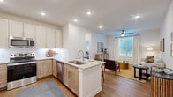 Located at 2300 N Friendship Rd in Sherman, TX, this thoughtfully designed one-bedroom, one-bathroom residence offers a cohesive open-concept layout with modern finishes throughout. The combined kitchen and living area forms the heart of the home, anchored by a central island with granite countertops, a built-in sink, and bar seating. The kitchen is outfitted with stainless steel appliances, including a refrigerator, range, and over-the-range microwave, complemented by two-tone cabinetry — white upper cabinets paired with warm wood lower cabinets. Light hardwood flooring flows throughout the main living areas, enhancing the bright, airy atmosphere. The living room benefits from large windows dressed with sheer curtains and blinds, allowing generous natural light, and features a ceiling fan overhead. The bedroom is a calm retreat with a ceiling fan, plush carpet, a large window, and direct access to a spacious walk-in closet equipped with multi-level shelving and hanging rods. The bathroom features wood-look flooring, a granite-topped vanity, and a full soaking tub with a shower. Clean white walls and recessed lighting throughout contribute to a modern, cohesive aesthetic.