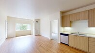 Located at 470 Alexander Loop in Eugene, Oregon, this single-floor unit offers three bedrooms and two full bathrooms in a thoughtfully designed layout. The open kitchen and living area anchors the space, featuring warm bamboo-style hardwood flooring that extends throughout. The kitchen is well-appointed with light wood cabinetry, stainless steel appliances including a refrigerator, range, microwave, and dishwasher, and a light-toned countertop with an undermount sink. The adjacent living area is filled with natural light from large windows that frame lush, mature tree views, creating a bright and welcoming atmosphere. A sliding glass door opens to a private balcony with a modern grid-railing, offering peaceful outdoor views of the surrounding greenery. The bedrooms are carpeted and feature windows overlooking the tree-lined surroundings, lending a quiet, comfortable feel. The primary bedroom provides a generous amount of space. Both bathrooms are finished in a clean, neutral palette — one featuring a vanity with light wood cabinetry and a tub/shower combination, and the second with a full tub/shower unit. A hallway connects the rooms, completing this efficient and comfortable floor plan.