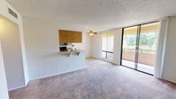 Located at 1901 E Osborne in Phoenix, Arizona, this single-floor residence offers a well-organized, open-concept layout designed for comfortable everyday living. The spacious living area features plush carpeting, a ceiling fan, and a textured ceiling, with natural light flowing in through large sliding glass doors that open onto a private balcony overlooking lush greenery.

The kitchen is thoughtfully designed in a galley style, featuring warm oak cabinetry that lines both walls, light-toned countertops, tile flooring, a double-basin sink, and black appliances including an electric range and built-in microwave. A peninsula counter with a breakfast bar connects the kitchen to the living area, creating a seamless and functional open flow.

The bedrooms are generously sized, each finished with soft carpeting and ceiling fans. One bedroom includes a mirrored sliding closet, adding a sense of depth and additional storage. The bathroom features a dual-sink vanity with oak cabinetry and light countertops, complemented by a separate water closet area with a bathtub and tile flooring.

Throughout the residence, a neutral color palette and consistent finishes create a cohesive and inviting ambiance, making this Phoenix home a practical and comfortable living space.