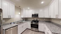 This single-floor residence offers a thoughtfully designed layout that maximizes functionality and comfort across its 1-bedroom, 1-bathroom floor plan. The kitchen serves as a standout feature, equipped with white shaker-style cabinetry extending to the upper walls, granite-patterned countertops, and a full suite of stainless steel appliances including a gas range, over-the-range microwave, dishwasher, and refrigerator. Recessed lighting and a pendant light above the sink illuminate the space, while light wood-look vinyl plank flooring ties the kitchen seamlessly into the adjoining living area.

The living area is generously proportioned, featuring the same wood-look vinyl plank flooring, neutral-toned walls, and clean white baseboards, offering a versatile canvas for a variety of furniture arrangements. The bedroom provides a comfortable retreat with soft carpeting, a window fitted with vertical blinds for natural light control, and a dedicated closet.

The bathroom is finished with large-format tile flooring, a white vanity with granite-style countertop, a framed mirror with vanity lighting, and a linen tower for additional storage. A dedicated laundry closet houses a full-sized washer and dryer, adding practical convenience to this well-rounded residence.