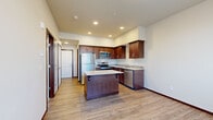 Located in Stanwood, WA, Unit 313 is a thoughtfully designed one-bedroom, one-bathroom residence that maximizes its efficient footprint with a functional, modern layout. The kitchen is the centerpiece of the home, showcasing rich dark-wood cabinetry, light quartz countertops, a decorative tile backsplash, and a full suite of stainless steel appliances including a refrigerator, range, microwave, and dishwasher. A central island provides additional prep space and casual seating, while recessed lighting overhead brightens the entire area. Light-toned hardwood-style flooring extends through the kitchen and hallway, lending a warm, cohesive feel. The hallway connects the main living area to the bedroom, bathroom, and entry, offering a sense of separation and privacy. The bedroom is a comfortable retreat, finished with soft wall-to-wall carpet, a sliding closet, and a window that lets in natural light. The bathroom features a rich wood vanity with a light countertop, a full tub-shower combination, and matching hardwood-style flooring. Clean white walls and neutral tones throughout create a bright, move-in-ready atmosphere well-suited for comfortable everyday living.