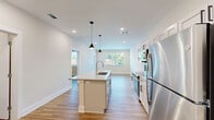 Located at 401 S Fourth St in Nashville, TN 37206, this well-appointed one-bedroom, one-bathroom unit offers a thoughtfully designed single-floor layout that maximizes every inch of its intimate footprint. Light-toned hardwood-style flooring runs throughout, tying each room together with a clean, cohesive aesthetic.

The kitchen is a standout feature, showcasing white shaker cabinetry, a bold navy subway tile backsplash, granite countertops, and a full suite of stainless steel appliances including a refrigerator, range, and microwave. A central island with an undermount sink and pendant lighting overhead adds both workspace and a stylish focal point that opens naturally into the living area.

The bedroom is a comfortable, well-proportioned retreat with a ceiling fan, natural light streaming through large windows fitted with blinds, and neutral walls that provide a calm, versatile backdrop. The bathroom is finished with a white shaker vanity, granite countertop, framed mirror with sconce lighting, and a tiled shower-tub combination — all carried on the same warm hardwood-style flooring.

A dedicated laundry room houses a full-size top-loading washer and dryer alongside overhead wire shelving for added storage. Recessed lighting and an access door to an outdoor area round out this move-in-ready Nashville residence.