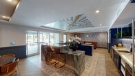 Located at 330 Westlake Ave in the Echo Park neighborhood of Los Angeles, this single-floor community lounge space showcases an elevated, boutique-inspired interior design. The space is anchored by a striking marble island and counter surfaces with rich veining, complemented by deep navy blue cabinetry throughout. A fully equipped wet bar features a patterned tile backsplash, undermount sink, under-counter refrigeration, and under-cabinet lighting, making it ideal for entertaining. The seating area includes tufted cognac leather banquette booths set against a decorative mosaic tile accent wall in muted blue and gray tones, with round marble-top tables and pendant lighting overhead. A separate dining area offers a dark wood round table with mid-century modern orange chairs, a large-screen television, and curated wall art that adds a contemporary cultural touch. Herringbone-patterned hardwood flooring flows throughout, grounding the space with warmth and texture. A coffered ceiling features a bold, hand-painted geometric mural as its centerpiece, lending artistic flair to the room. Floor-to-ceiling sliding glass doors open to an outdoor area, flooding the interior with natural light and providing a seamless indoor-outdoor connection.