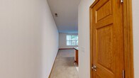 Located at 0N295B Dooley Dr in Geneva, IL, this efficiently designed single-floor unit offers a well-organized layout comprising a combined kitchen and living room alongside a full bathroom. The kitchen is a standout feature, outfitted with warm honey-toned wood cabinetry that extends to the ceiling for ample storage, dark granite countertops, and a full suite of stainless steel appliances including a refrigerator, range, built-in microwave, and dishwasher. A peninsula with matching granite provides additional prep and dining space, seamlessly connecting the kitchen to the living area. The flooring transitions from light ceramic tile in the kitchen to plush neutral carpet in the living room, which is bathed in natural light through large windows offering pleasant views of surrounding greenery. The living area's clean white walls and open layout create a bright, airy atmosphere. The bathroom features a full soaking tub and shower combination with a classic white surround, complemented by safety grab bars, tile flooring, and warm wood baseboards consistent throughout the unit. Overall, the space delivers a functional and comfortable living environment with thoughtful finishes.