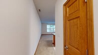 Located at 0N295B Dooley Dr in Geneva, IL, this efficiently designed single-floor unit offers a well-organized layout comprising a combined kitchen and living room alongside a full bathroom. The kitchen is a standout feature, outfitted with warm honey-toned wood cabinetry that extends to the ceiling for ample storage, dark granite countertops, and a full suite of stainless steel appliances including a refrigerator, range, built-in microwave, and dishwasher. A peninsula with matching granite provides additional prep and dining space, seamlessly connecting the kitchen to the living area. The flooring transitions from light ceramic tile in the kitchen to plush neutral carpet in the living room, which is bathed in natural light through large windows offering pleasant views of surrounding greenery. The living area's clean white walls and open layout create a bright, airy atmosphere. The bathroom features a full soaking tub and shower combination with a classic white surround, complemented by safety grab bars, tile flooring, and warm wood baseboards consistent throughout the unit. Overall, the space delivers a functional and comfortable living environment with thoughtful finishes.