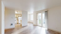 This thoughtfully designed 2-bedroom, 2-bathroom single-floor residence offers a bright and functional layout throughout. Light wood-style flooring flows through the open living, dining, and kitchen areas, creating a cohesive and airy atmosphere. The living room is bathed in natural light from large windows and a sliding glass door that leads to a covered private balcony, where views of well-maintained green landscaping and surrounding trees provide a serene outdoor retreat.

The kitchen features warm wood-toned cabinetry, white appliances including a refrigerator and range, and connects seamlessly to the dining area, making it ideal for everyday living and entertaining. A hallway leads to the two bedrooms, each offering a comfortable and quiet setting. The primary bedroom is generously sized with plush carpeting, a large window overlooking greenery, and a built-in closet. The second bedroom also features carpeting and ample natural light. Four closets are distributed throughout the home, providing excellent storage capacity.

Both bathrooms are clean and functional, with one featuring a walk-in shower and an adjacent built-in shelving unit for added convenience. An in-unit laundry area adds practical ease to daily routines. The entrance and hallway connect all spaces efficiently, completing this well-organized and comfortable home.