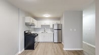 Located at 3170 Cleveland Ave in Columbus, Ohio, this single-floor home offers four bedrooms, one bathroom, a living room, kitchen, and hallway within a compact and efficiently designed layout. Light gray walls and wood-look luxury vinyl plank flooring run consistently throughout, creating a cohesive and clean aesthetic across all rooms.

The kitchen is a standout feature, equipped with white shaker-style cabinetry, marble-look countertops, a stainless steel refrigerator, a gas range, and an under-cabinet range hood. A single-basin sink with a modern gooseneck faucet completes the functional workspace.

The four bedrooms are finished in the same neutral gray palette with clean white trim and baseboards. Several bedrooms include sliding-door closets with built-in shelving, offering practical storage solutions. The primary bedroom features two windows that bring in natural light and includes a wall-mounted HVAC unit. Additional bedrooms provide versatile spaces suitable for a variety of uses.

The bathroom is cleanly appointed with a white vanity, single-basin sink, brushed nickel fixtures, a wall mirror, and a full tub-shower combination. A connecting hallway ties the rooms together, supporting a straightforward and navigable floor plan throughout the home.