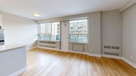 Located on the fifth floor at 321 Sherbourne Street in Toronto's St. James Town neighbourhood, this 2-bedroom, 1-bathroom unit offers a practical and well-appointed layout across a single floor. Light hardwood flooring runs throughout the entire unit, creating a warm, cohesive feel from room to room. The entrance opens into a hallway that connects the key living spaces efficiently.

The galley-style kitchen features white cabinetry with brushed nickel hardware, white subway tile backsplash, light countertops, and stainless steel appliances including a full-size refrigerator and stove. The kitchen flows into a combined dining and living area, which is bathed in natural light through large windows that frame urban Toronto views. Access to the balcony extends the living space outdoors with additional city sightlines.

Both bedrooms are comfortably sized with neutral grey walls, light hardwood floors, and ample closet space — the unit includes four closets in total. The primary bedroom features a wide window with open views of the surrounding cityscape. The bathroom is finished with clean white subway tile surrounding a soaker tub, complemented by a granite-style vanity countertop. The unit's overall aesthetic is clean, bright, and move-in ready.