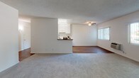 This single-floor residence at 11901 176th St in Artesia, California offers a functional and well-maintained layout with a clean, neutral aesthetic throughout. The galley-style kitchen is thoughtfully designed with white cabinetry, granite-look countertops, a double stainless steel sink, a gas range, and a full-size refrigerator. Durable hardwood-style flooring runs through the kitchen and dining area, adding warmth and contrast to the bright white finishes. The open living and dining area is generously proportioned, featuring a ceiling fan, a wall-mounted HVAC unit, and large windows dressed with vertical blinds that invite ample natural light. A peninsula counter connects the kitchen to the living space, enhancing the open flow between the two areas. The bedrooms are carpeted and serene, each with windows that bring in natural light and views of surrounding greenery. One bedroom includes a sliding mirrored closet, while another features a walk-in closet with shelving. The unit includes two bathrooms: one with a combined tub and shower enclosed in a glass sliding door, a vanity, and a small window for ventilation; and a second with a vanity and access to an additional shower. The textured ceilings and soft, neutral wall tones create a cohesive and understated ambiance throughout the home.