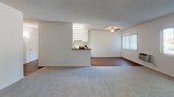 This single-floor residence at 11901 176th St in Artesia, California offers a functional and well-maintained layout with a clean, neutral aesthetic throughout. The galley-style kitchen is thoughtfully designed with white cabinetry, granite-look countertops, a double stainless steel sink, a gas range, and a full-size refrigerator. Durable hardwood-style flooring runs through the kitchen and dining area, adding warmth and contrast to the bright white finishes. The open living and dining area is generously proportioned, featuring a ceiling fan, a wall-mounted HVAC unit, and large windows dressed with vertical blinds that invite ample natural light. A peninsula counter connects the kitchen to the living space, enhancing the open flow between the two areas. The bedrooms are carpeted and serene, each with windows that bring in natural light and views of surrounding greenery. One bedroom includes a sliding mirrored closet, while another features a walk-in closet with shelving. The unit includes two bathrooms: one with a combined tub and shower enclosed in a glass sliding door, a vanity, and a small window for ventilation; and a second with a vanity and access to an additional shower. The textured ceilings and soft, neutral wall tones create a cohesive and understated ambiance throughout the home.