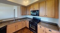 Located at 9920 W Camelback Rd in Phoenix, Arizona, this single-floor residence offers a thoughtfully designed layout with a variety of functional and comfortable spaces throughout. The main living area is a standout, featuring a cozy fireplace with a built-in niche above, crown molding, and multiple windows that allow abundant natural light to fill the room. A ceiling fan and pendant light add to the ambiance, while plush carpeting underfoot provides warmth and comfort. The kitchen is well-equipped with light maple cabinetry, dark granite countertops, a gas range, built-in microwave, and hardwood flooring that extends into the hallway, giving the space a polished feel. The bedrooms are carpeted and bright, each benefiting from natural light through blinds-fitted windows, with ceiling fans providing year-round comfort. One bedroom includes a sliding glass door that opens to an outdoor area. The spacious walk-in closet offers generous built-in shelving and hanging space. The bathrooms are finished with tile flooring and warm wood cabinetry — one featuring a tub/shower combo, the other a walk-in shower with a sliding glass door and a single vanity sink. A textured-wall hallway connects the living spaces seamlessly, completing this well-maintained Phoenix residence.